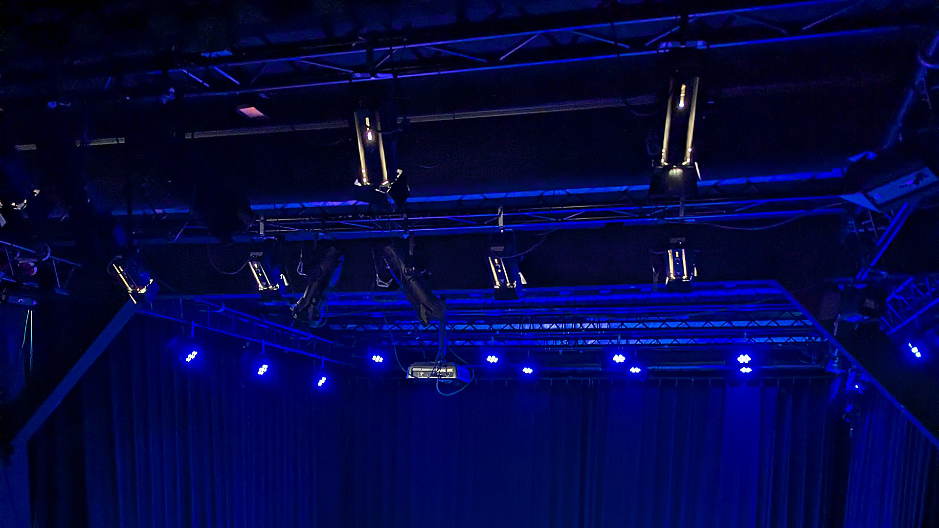 Truss met theaterlampen boven een podium in blauw licht